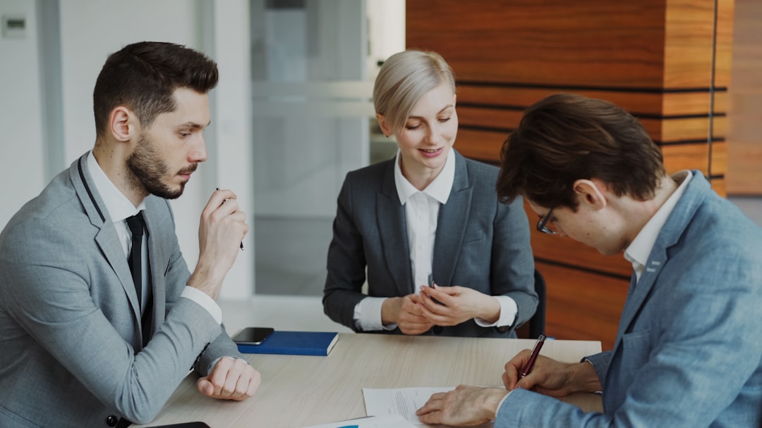 Three professionals discussing and signing a document at a table